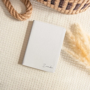 May include: White leather notebook with the name "Zander" embossed in black lettering.