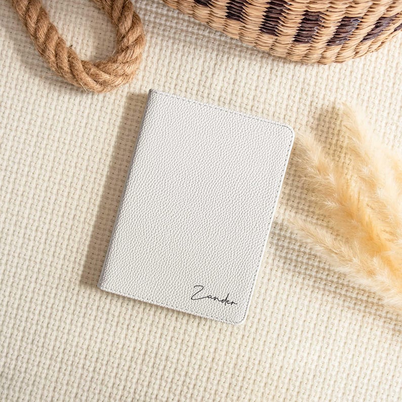 May include: White leather notebook with the name "Zander" embossed in black lettering.