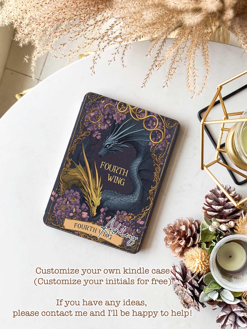Puede incluir: Una funda Kindle personalizada con un fondo morado y un dise&ntilde;o de drag&oacute;n dorado y azul. El texto "FOURTH WING" est&aacute; impreso en la funda. El nombre "Ashley" est&aacute; escrito en cursiva en la esquina inferior derecha de la funda.