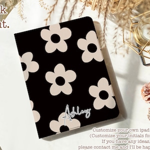 Peut inclure: Étui noir pour iPad avec un motif de marguerites blanches et le nom "Ashley" écrit en cursive. Personnalisez votre propre étui pour iPad avec vos initiales gratuitement.