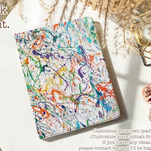 Peut inclure: Une coque d'iPad blanche avec un motif de peinture éclaboussée de couleurs. Le nom "Ashley" est écrit en cursive sur le devant de la coque. Le texte "Personnalisez votre propre coque d'iPad (Personnalisez vos initiales gratuitement) Si vous avez des idées, n'hésitez pas à me contacter et je serai ravi de vous aider !" est écrit sous la coque.