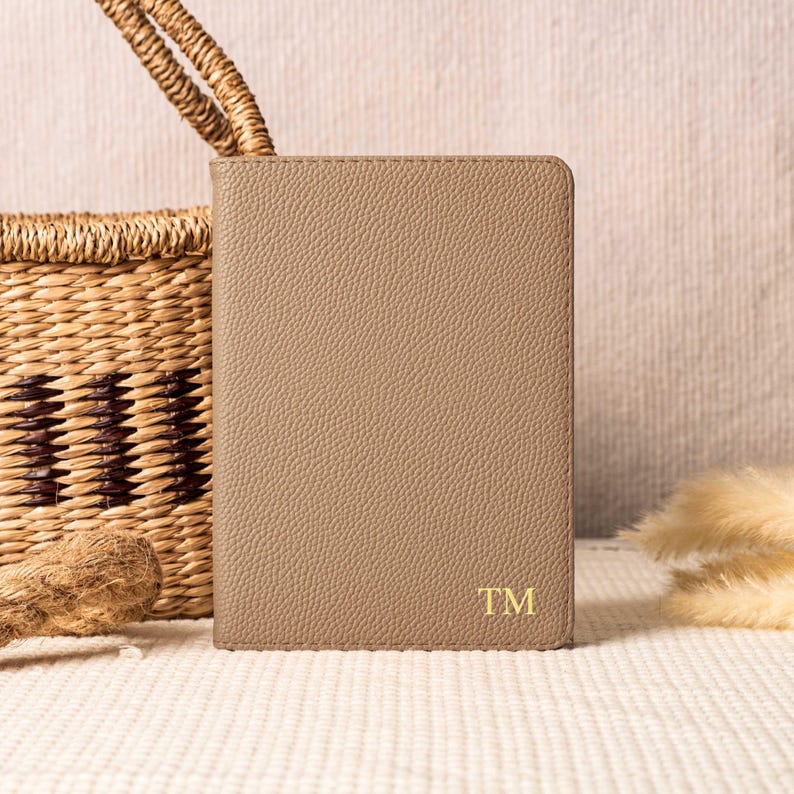 May include: A light brown leather notebook with the initials "TM" embossed in gold on the front cover.