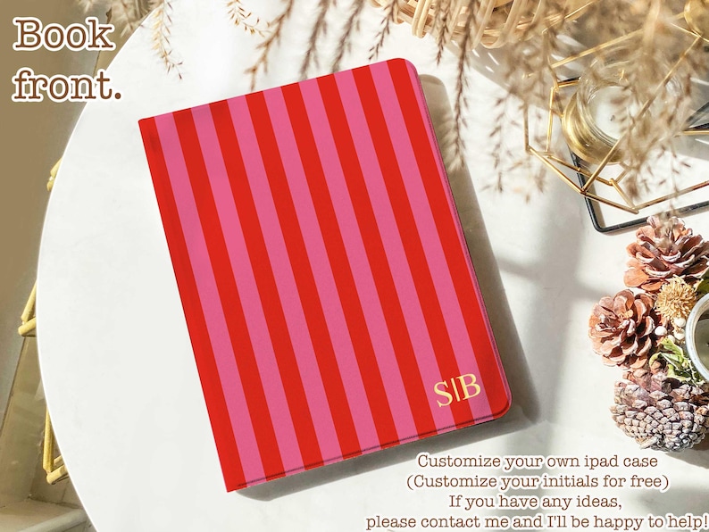 May include: A rectangular tablet case featuring a vibrant pattern of vertical red and pink stripes. The bottom right corner displays the gold-colored initials S|B. The case has a smooth, flat surface and a clean, modern rectangular shape.