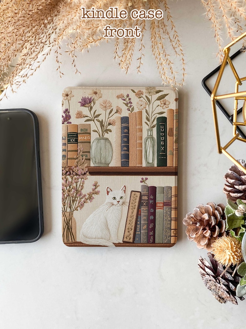Pode incluir: Um gato branco est&aacute; sentado em uma prateleira com uma cole&ccedil;&atilde;o de livros e flores secas. A prateleira faz parte de uma capa para Kindle com um design floral.