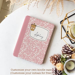 以下が含まれることがあります： ピンクと白の模様の入ったKindleケース。名前は「Ashley」とパーソナライズされており、猫の顔をした漫画のコーヒーカップが描かれています。自分のイニシャルでKindleケースをカスタマイズしましょう。無料です。