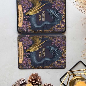 Puede incluir: Una funda para lector electr&oacute;nico negra y dorada con un dise&ntilde;o floral y dos dragones entrelazados. El texto "Fourth Wing" se repite en la funda.