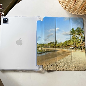 May include: A clear TPU case with a tropical beach scene printed on the back. The case is designed for an iPad or tablet and has a flip cover.