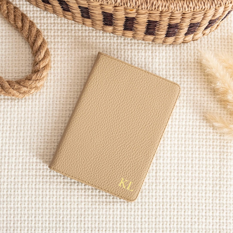 May include: A beige leather journal with the initials "KL" embossed in gold on the front cover.