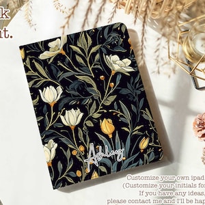 Puede incluir: Una funda negra para iPad con un patrón floral que presenta flores blancas, hojas verdes y detalles amarillos. El nombre "Ashley" está escrito en blanco en la funda. El texto "Personaliza tu propia funda para iPad (Personaliza tus iniciales gratis) Si tienes alguna idea, ponte en contacto conmigo y estaré encantado de ayudarte!" está escrito debajo de la funda.