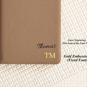 May include: A brown leather notebook with the name "Thomas" and the letters "TM" engraved in gold. The text "Laser Engraving (The Font of the Font Table)" and "Gold Embossing (Fixed Font)" are written in black text on a white background.