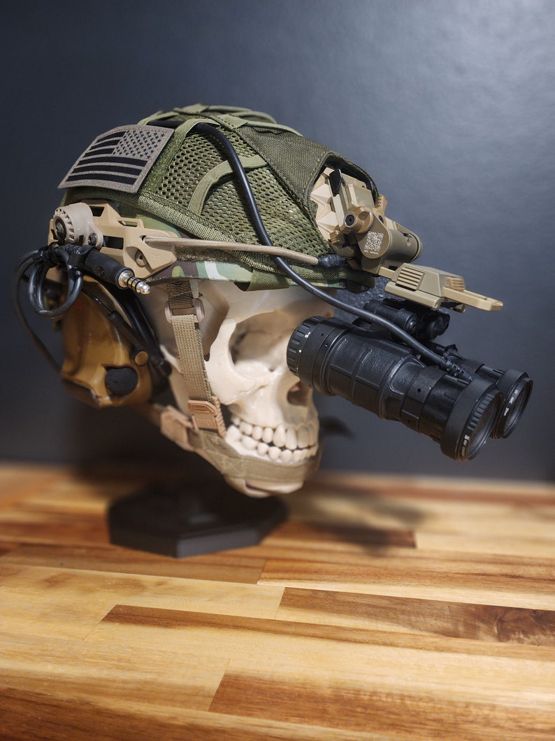 Pu&ograve; includere: Un casco tattico con visore notturno, montato su un teschio. Il casco presenta un motivo mimetico, una toppa con la bandiera americana e vari accessori. Il visore notturno &egrave; nero, a tema militare.