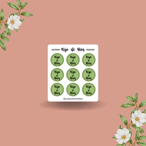 May include: Nine green and white circular stickers with the text "Hijo de Dios" in black lettering. The stickers are arranged in three rows of three. The text "@LovelyLatinaCreations" is at the bottom of the image.