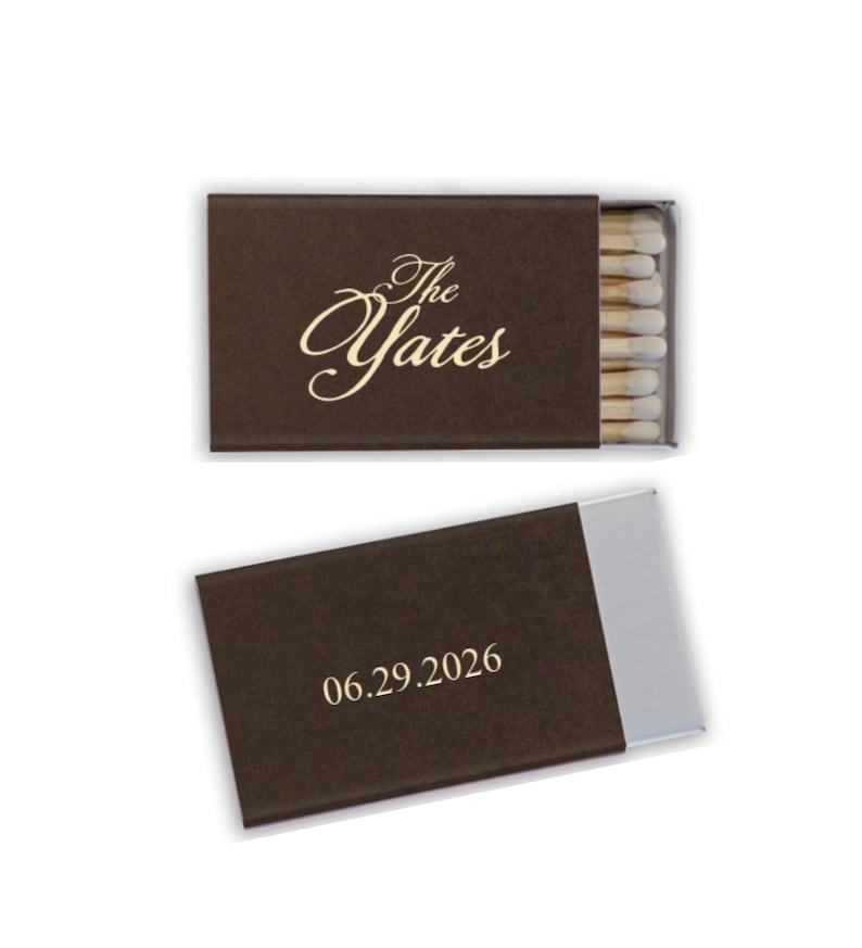 May include: Two brown matchboxes, one open and one closed, against a white background. The closed box has the text "The Yates" in gold script. The open box displays the date "06.29.2026" in a simple font.