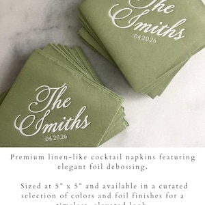 May include: A stack of sage green square cocktail napkins featuring white foil debossed text that reads The Smiths and the date 04.20.26. The napkins measure 5 inches by 5 inches and have a textured finish resembling linen fabric.