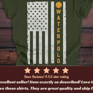 Puede incluir: Una camiseta verde militar con un gr&aacute;fico blanco desgastado de la bandera estadounidense. El dise&ntilde;o incluye un icono de pelota de waterpolo amarilla sobre el texto vertical "WATERPOLO" en letras may&uacute;sculas amarillas, sobre las rayas de la bandera.