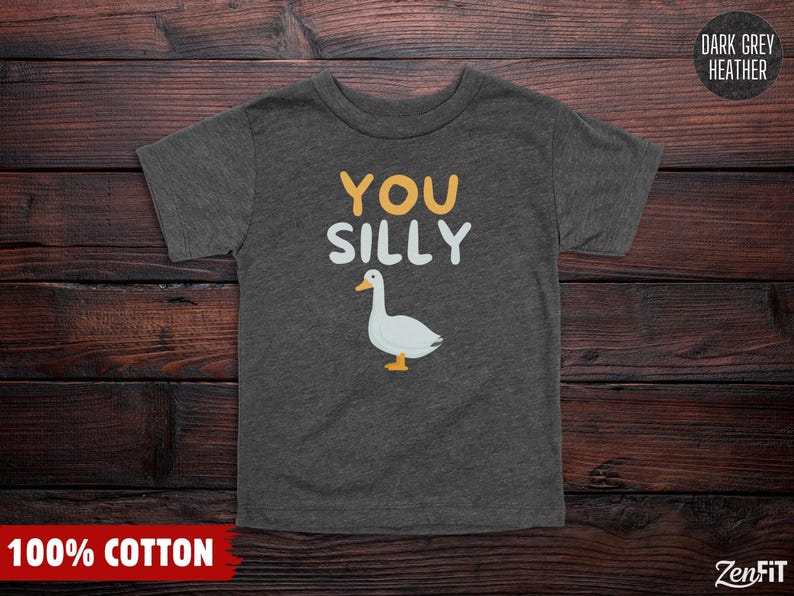 K&ouml;nnte beinhalten: Ein dunkelgrau meliertes Kurzarm-T-Shirt mit dem Text YOU SILLY in gelben und wei&szlig;en Buchstaben &uuml;ber einer Grafik einer wei&szlig;en Gans mit orangefarbenem Schnabel und F&uuml;&szlig;en. Das T-Shirt ist als 100% Baumwolle gekennzeichnet.