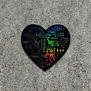 May include: A black heart-shaped sticker with a circuit board design. The circuit board is outlined in rainbow colors.