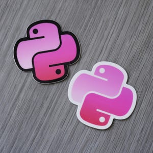 May include: Two stickers featuring the Python programming language logo. The logo is a stylized snake in shades of pink, with a black outline and two black dots. The stickers are on a gray, textured surface.