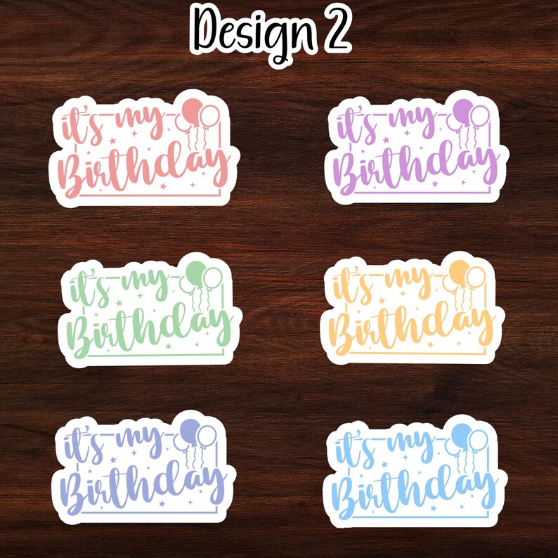 Puede incluir: Seis pegatinas coloridas con el texto "it's my Birthday" y globos. Las pegatinas est&aacute;n sobre un fondo de madera.