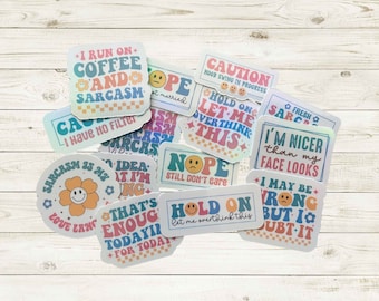May include: A collection of colorful, holographic stickers with humorous phrases. The stickers feature text like "I run on coffee and sarcasm," "I'm nicer than my face looks," and "Hold on, let me overthink this."