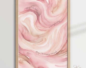 May include: Pink and peach watercolor print with the text "May I be held in lovingkindness. May I be happy and safe."  The print is framed in a light wood frame. The text "Self Care Prints LC" is in the bottom right corner.