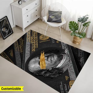 May include: Black and gold rug with a repeated pattern of US $100 bills. The bills are faded and the image of Benjamin Franklin is partially obscured by a gold paint stroke.