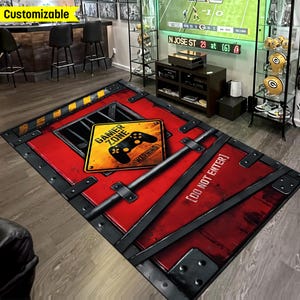 May include: A red and black gamer zone rug with a warning sign that says "Gamer Zone" and "Warning". The rug also has a black metal door with the text "Do Not Enter!" on it.