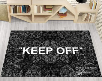 Könnte beinhalten: Ein schwarz-weißer Teppich mit einem geometrischen Muster und dem Text "KEEP OFF" in Weiß. Der Teppich wurde von Virgil Abloh für IKEA entworfen und ist mit "Flooring" sowie dem Ort "Almhult, Schweden" und dem Jahr "c.2019" gekennzeichnet.