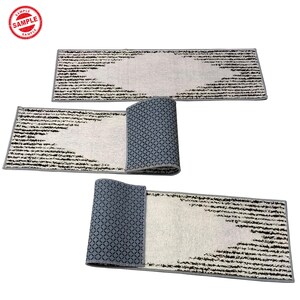 Puede incluir: Tres alfombras de pasillo grises y blancas con un dise&ntilde;o geom&eacute;trico negro. Las alfombras est&aacute;n dobladas por la mitad y colocadas sobre una superficie blanca.