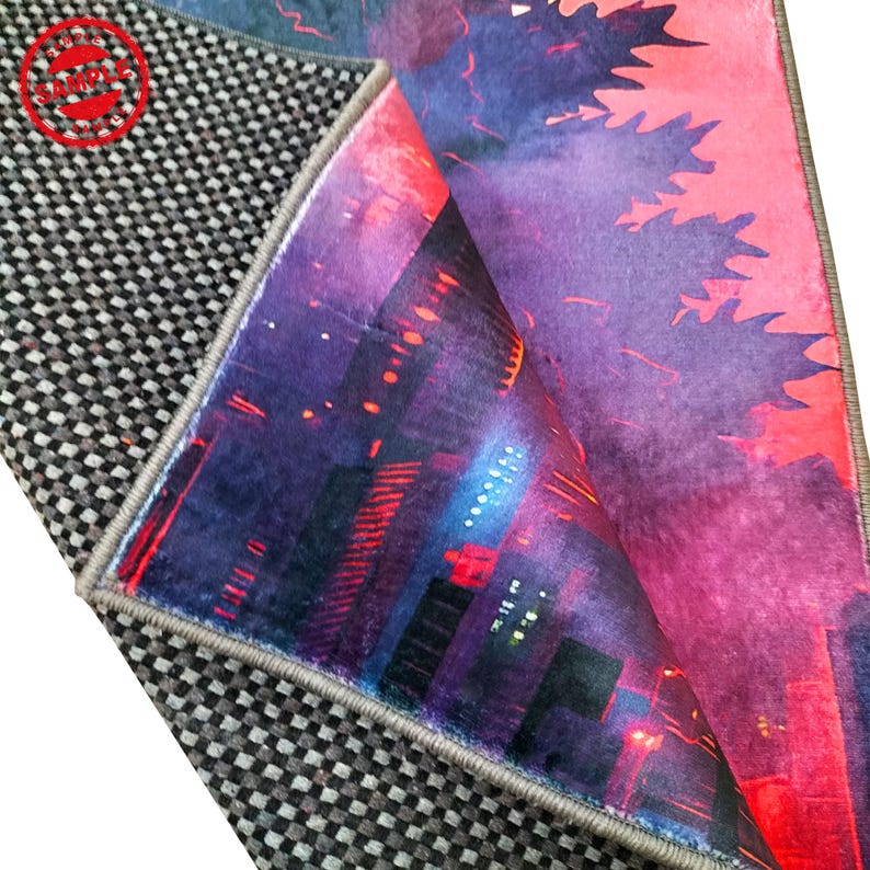 May include: Close-up of the edge of a rug with a Godzilla-themed design. The rug features a purple and pink cityscape with Godzilla in the background. The rug has a gray backing with a checkered pattern.