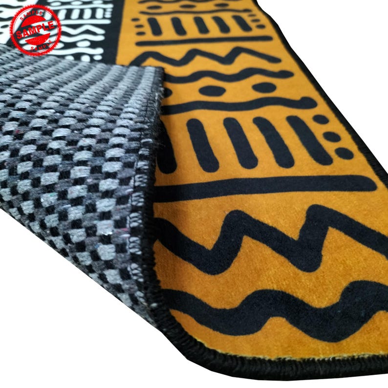 May include: A close-up of a black and yellow rug with geometric patterns. The rug has a black border and a gray backing.