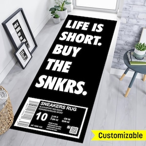 May include: Black and white doormat with the text "Life is short. Buy the SNKRS."  The doormat also has a white label with the text "Sneakers Rug" and size information in US, UK, BR, CM, and EUR sizes.