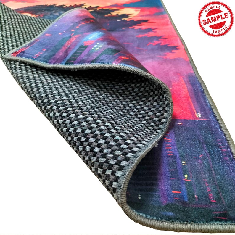 May include: A close-up of the back side of a rug with a gray checkered pattern. The rug has a colorful design on the front side, featuring a cityscape with a sunset in the background. The rug has a gray border.