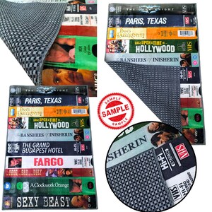 Może przedstawiać: Prostokątny dywan z szaro-białym wzorem w kratę, z zestawem kaset VHS z tytułami film&oacute;w, takimi jak "Paris, Texas" i "Sexy Beast". Dywan ma estetykę retro, ze stemplem "Sample".