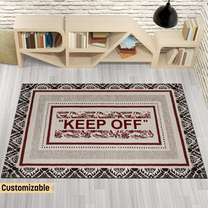 Può includere: Un tappeto beige e nero con motivo e un bordo rosso con il testo "KEEP OFF" in lettere rosse.