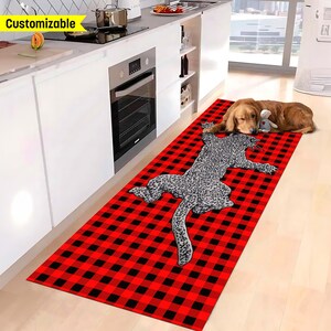 May include: A red and black checkered rug with a gray and white leopard print design. A brown dog is lying on the rug.