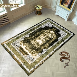 May include: A rectangular rug with a central design in shades of olive green and cream, framed by a white and green border. The rug is placed on a light-colored tiled floor. A rosary with a cross lies nearby.