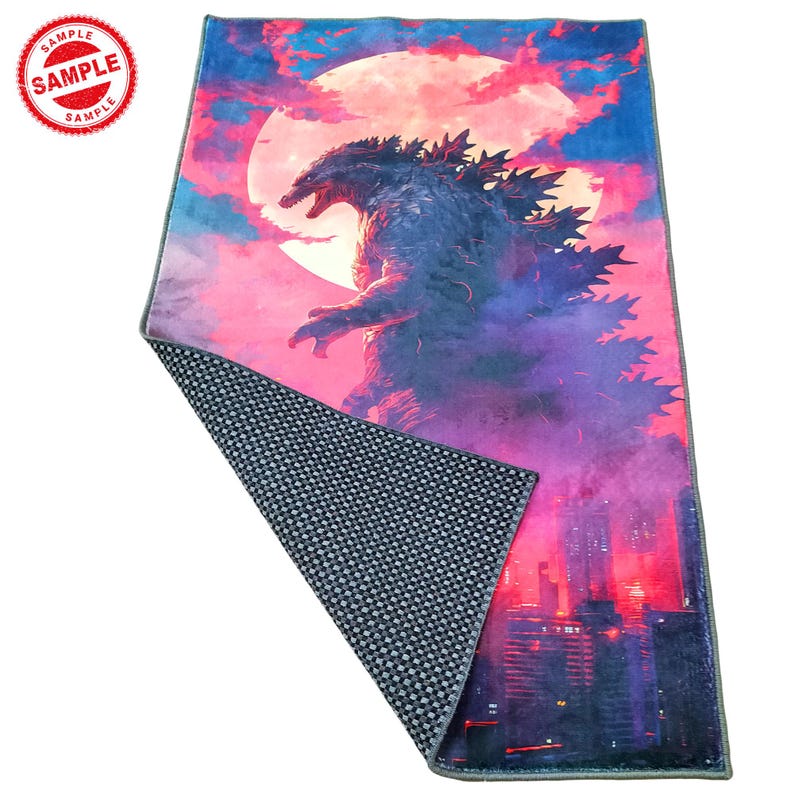 May include: A large, colorful rug featuring a Godzilla-like monster standing in front of a large, pink moon. The monster is dark blue and has a spiky back. The background is a pink and purple sky with a cityscape in the distance.