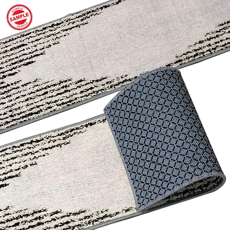 Puede incluir: Un tapete de corredor blanco y negro con un respaldo antideslizante gris. El tapete tiene un dise&ntilde;o moderno con l&iacute;neas negras y un fondo blanco.