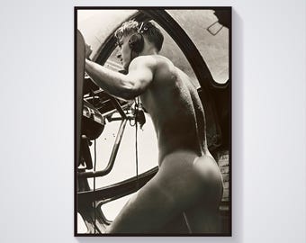 May include: A black and white photograph of a man in a cockpit, wearing headphones and looking to the left. He is nude from the waist up.