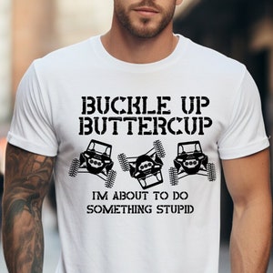 May include: White t-shirt with black text that reads "Buckle Up Buttercup I'm About To Do Something Stupid". The text is surrounded by three black images of off-road vehicles.