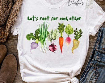 Könnte beinhalten: Weißes T-Shirt mit dem Text "Let's root for each other" und einer Reihe bunter Gemüse, darunter eine Karotte, eine Zwiebel, ein Radieschen, eine Rübe und eine Rote Bete.