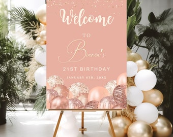 May include: A pink welcome sign on a wooden easel, with gold glitter accents and balloons. The sign reads "Welcome to Bianca's 21st Birthday" with the date. The sign is decorated with gold, white, and rose gold balloons.