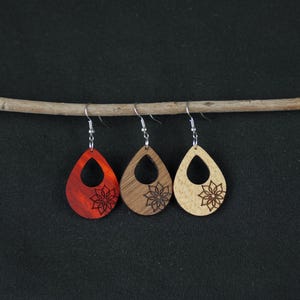 May include: Three pairs of wooden teardrop earrings with a laser-cut floral design. One pair is red, and the other two pairs are natural wood.