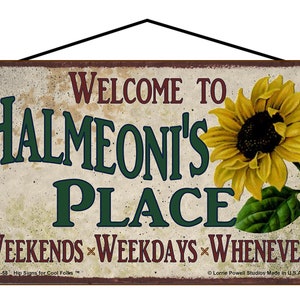 May include: A rectangular sign with the text "WELCOME TO HALMEONI'S PLACE" in green and maroon lettering. A yellow sunflower is on the right. The sign also reads "WEEKENDS WEEKDAYS WHENEVER".