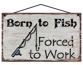 May include: Wooden sign with the text "Born to Fish Forced to Work" in black lettering. A fishing rod graphic is in the center. The sign has a distressed, rustic look with a black hanging wire.