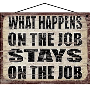 May include: A rectangular wooden sign with the text "WHAT HAPPENS ON THE JOB STAYS ON THE JOB" in black letters. The sign has a distressed, vintage look with a black hanging cord.
