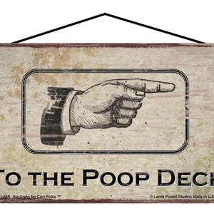 May include: A rustic wooden sign with a distressed white background and black text that reads "TO THE POOP DECK". A black and white illustration of a hand pointing to the right is above the text. The sign has a brown border and a black string for hanging.