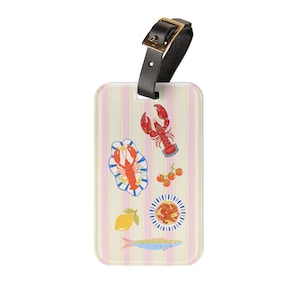 May include: A rectangular luggage tag with a light pink and cream vertical striped background. The tag features illustrations of a red lobster, a lobster on a blue and white plate, a lemon, cherry tomatoes, a small bowl of food, and a blue fish.