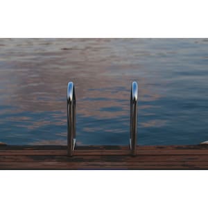 May include: A pair of silver metal handrails on a wooden dock over a body of water.